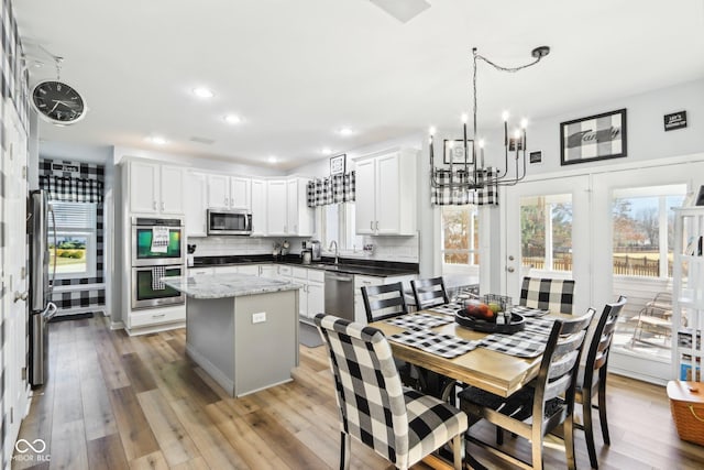 kitchen featuring a sink, decorative backsplash, stainless steel appliances, light wood-style floors, and a center island