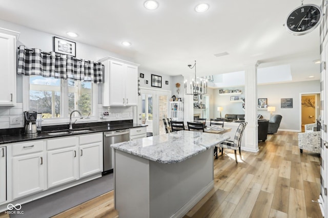 kitchen with light wood-type flooring, a sink, open floor plan, decorative backsplash, and dishwasher