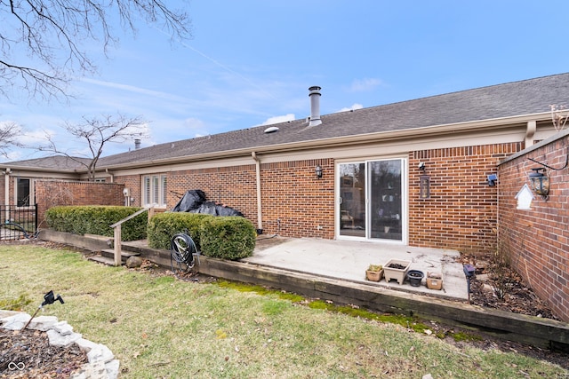 back of property with a lawn, brick siding, and a patio area