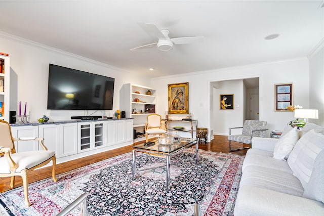 living room with built in shelves, baseboards, ceiling fan, ornamental molding, and wood finished floors