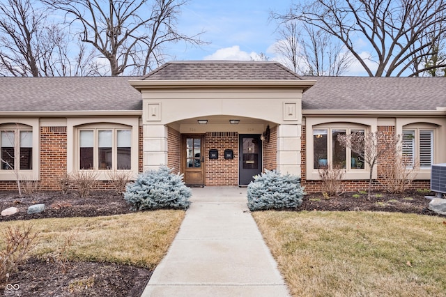 view of front facade featuring brick siding, a shingled roof, and a front lawn