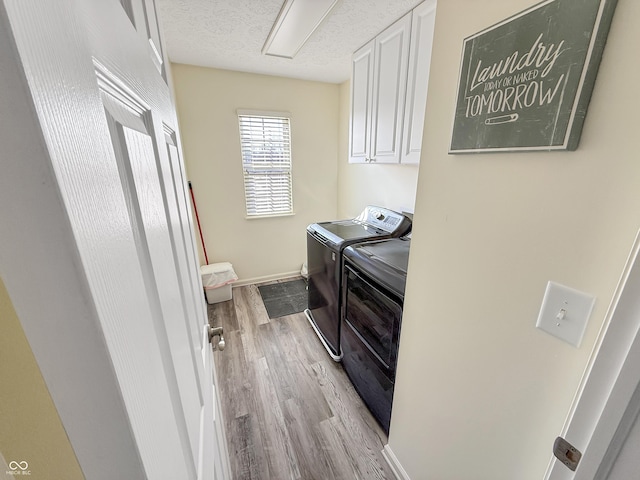 laundry room with baseboards, light wood-style flooring, cabinet space, a textured ceiling, and independent washer and dryer