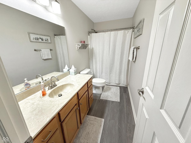 bathroom featuring curtained shower, toilet, wood finished floors, a textured ceiling, and vanity