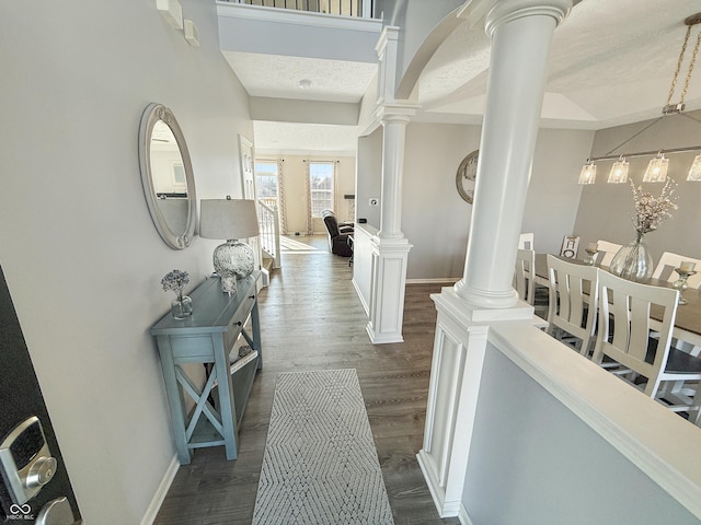 hall with decorative columns, baseboards, and dark wood-type flooring