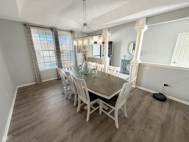 dining area featuring lofted ceiling, baseboards, dark wood-style flooring, and ornate columns