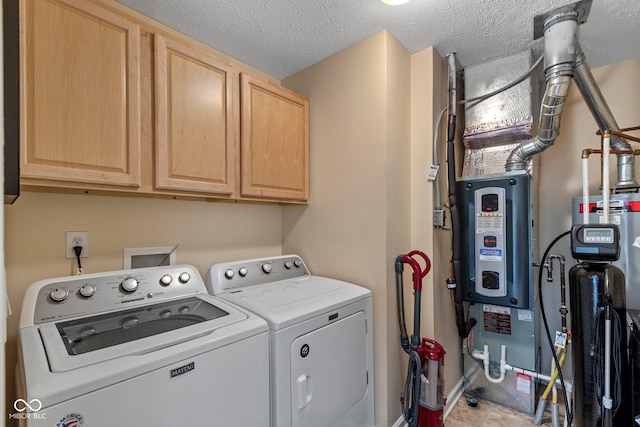 laundry room featuring washing machine and clothes dryer, cabinet space, and a textured ceiling