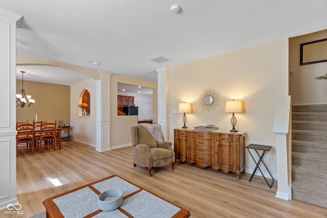 living room featuring light wood finished floors, visible vents, stairs, and an inviting chandelier