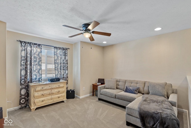 living area featuring light colored carpet, baseboards, and a textured ceiling