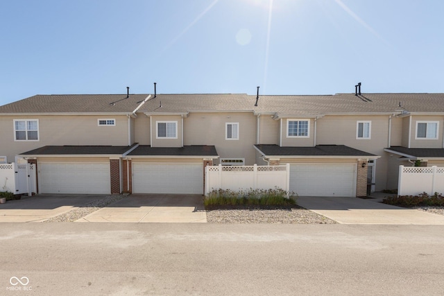 view of property with concrete driveway, fence, and a garage