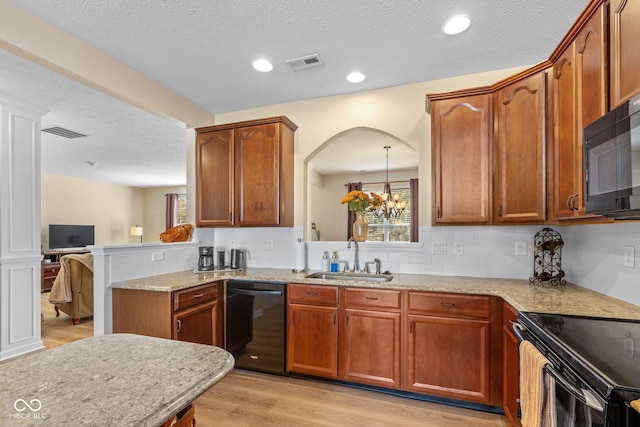 kitchen featuring a sink, visible vents, light wood-style floors, and black appliances