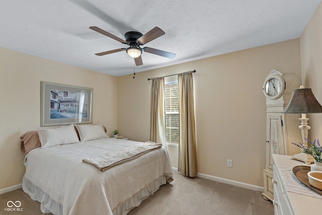 bedroom with light carpet, ceiling fan, a textured ceiling, and baseboards