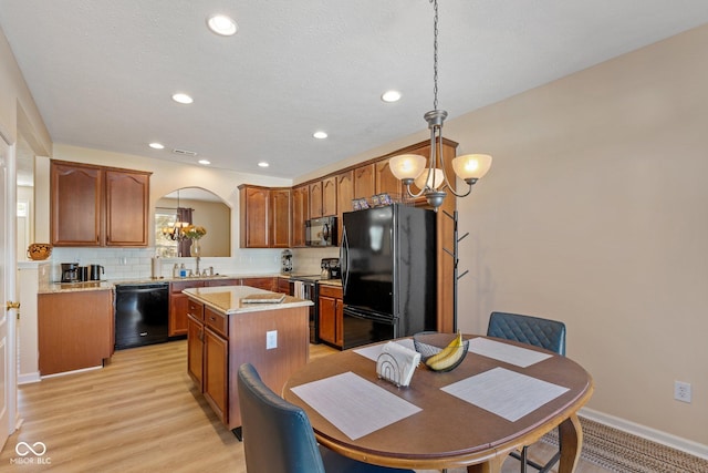 kitchen featuring an inviting chandelier, black appliances, decorative backsplash, and a kitchen island