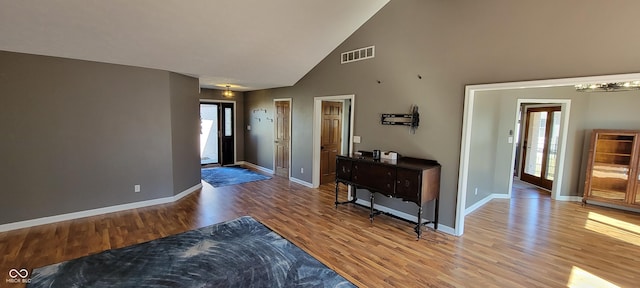 entrance foyer featuring visible vents, baseboards, high vaulted ceiling, and wood finished floors