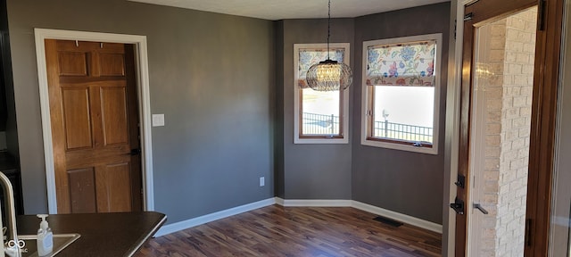 unfurnished dining area featuring dark wood finished floors, visible vents, and baseboards