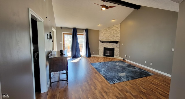 living room with wood finished floors, baseboards, high vaulted ceiling, beam ceiling, and a stone fireplace