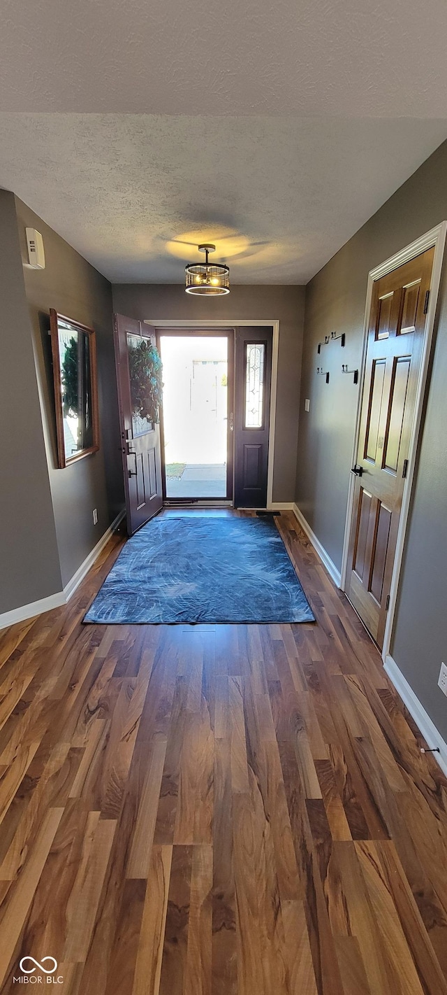 entryway featuring a textured ceiling, baseboards, and wood finished floors