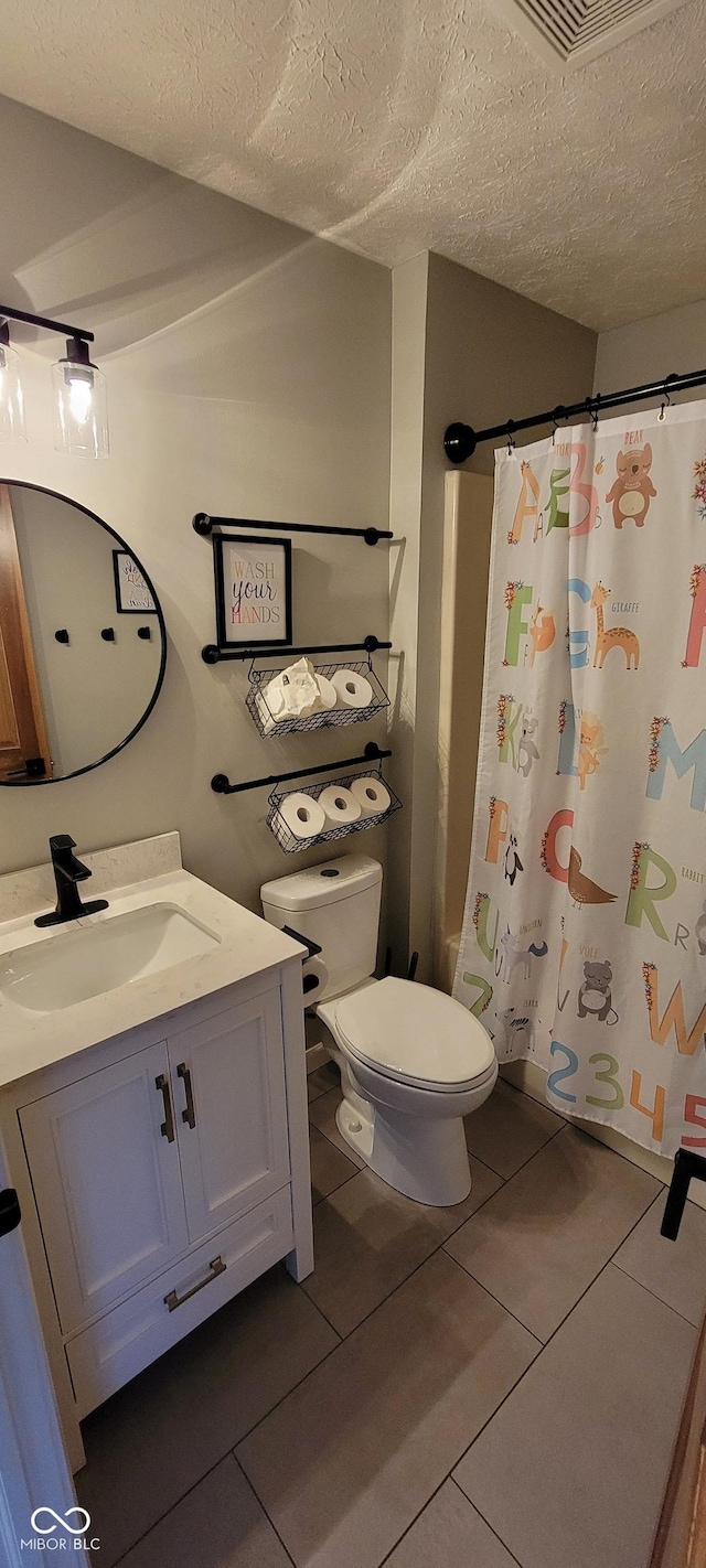 bathroom with visible vents, toilet, vanity, tile patterned floors, and a textured ceiling