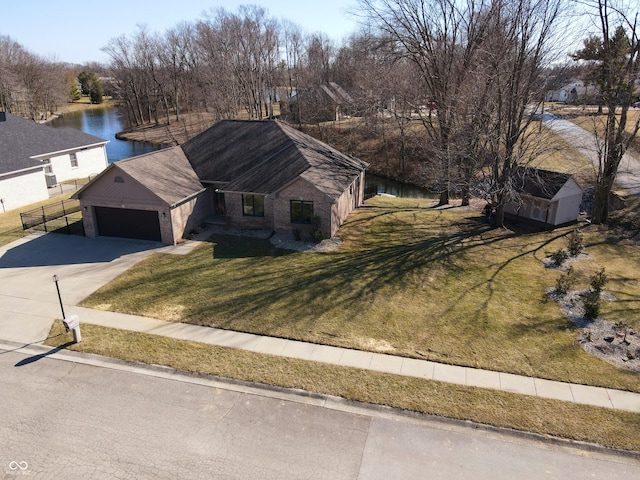 ranch-style home featuring a front lawn, a water view, fence, concrete driveway, and a garage