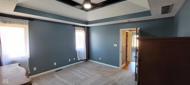 unfurnished bedroom featuring visible vents and a raised ceiling