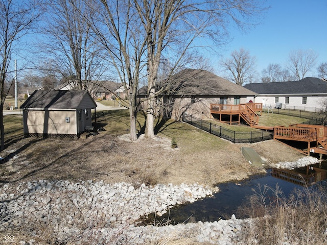 view of yard with stairway, a wooden deck, a fenced backyard, an outdoor structure, and a storage unit