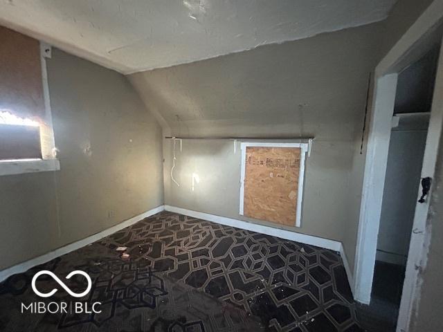 additional living space featuring baseboards and vaulted ceiling