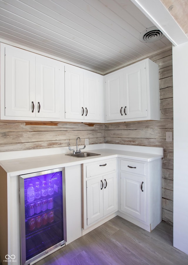 kitchen with visible vents, a sink, light countertops, wine cooler, and white cabinetry