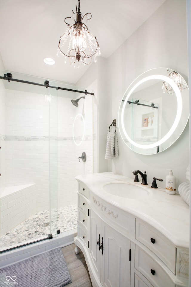 full bathroom featuring a notable chandelier, a shower stall, vanity, and wood finished floors