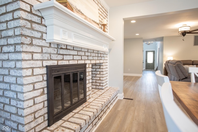 living room featuring wood finished floors, baseboards, visible vents, recessed lighting, and a fireplace