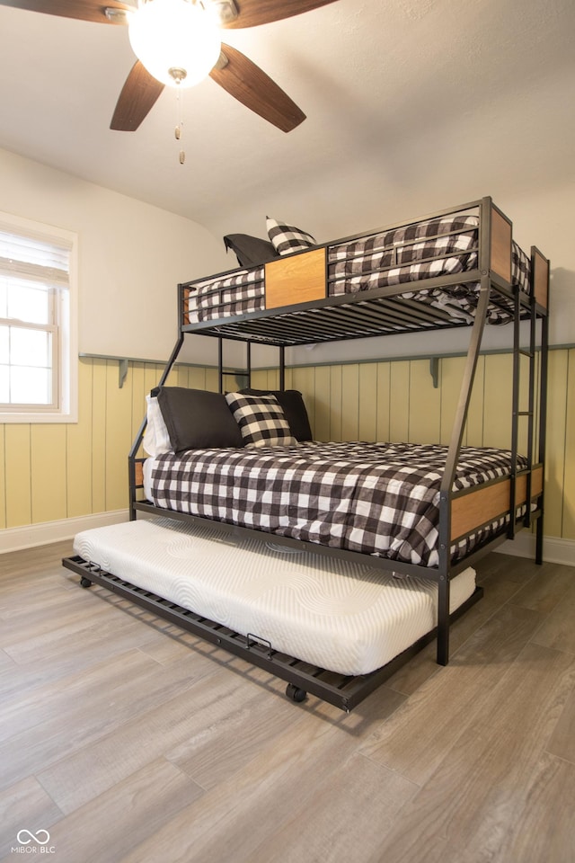 bedroom with a wainscoted wall and wood finished floors