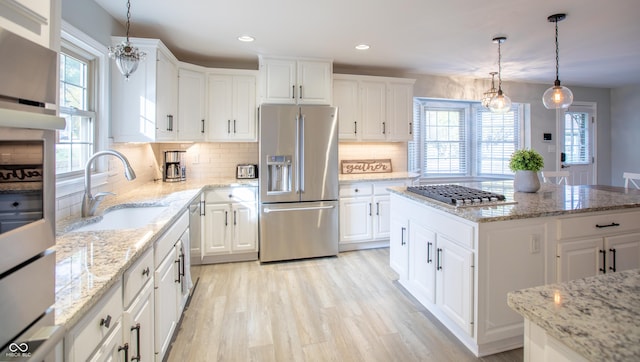 kitchen featuring appliances with stainless steel finishes, white cabinetry, light wood-type flooring, and a sink