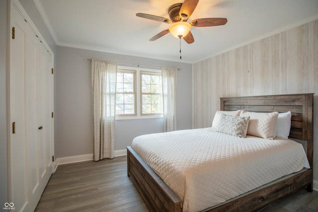 bedroom featuring a ceiling fan, wood finished floors, baseboards, ornamental molding, and a closet