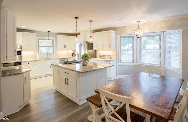 kitchen with backsplash, a center island, light wood-type flooring, appliances with stainless steel finishes, and a sink