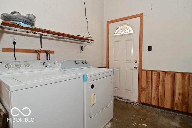 laundry room featuring laundry area, washing machine and dryer, wooden walls, and a wainscoted wall