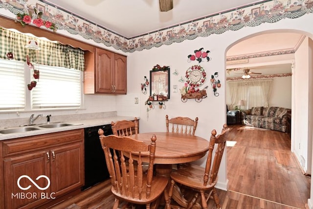 dining room with arched walkways, a ceiling fan, and wood finished floors