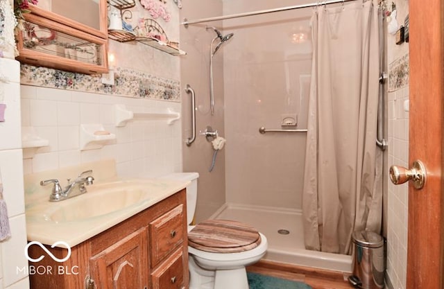 bathroom featuring vanity, a shower stall, toilet, and tile walls