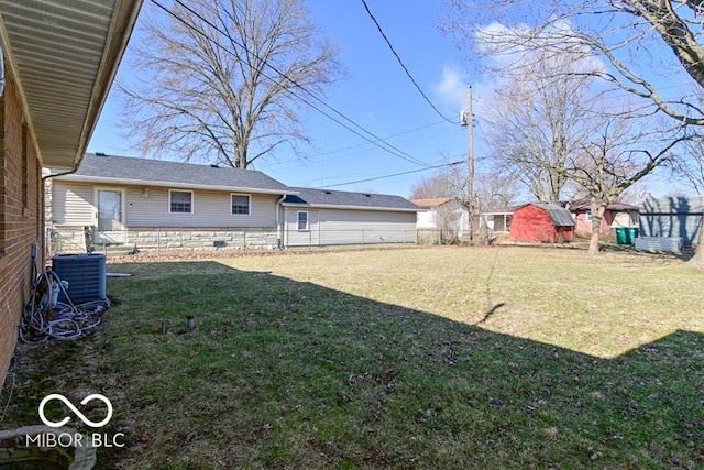 view of yard with central air condition unit, an outbuilding, and fence