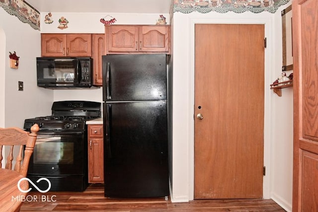 kitchen featuring black appliances, wood finished floors, and light countertops