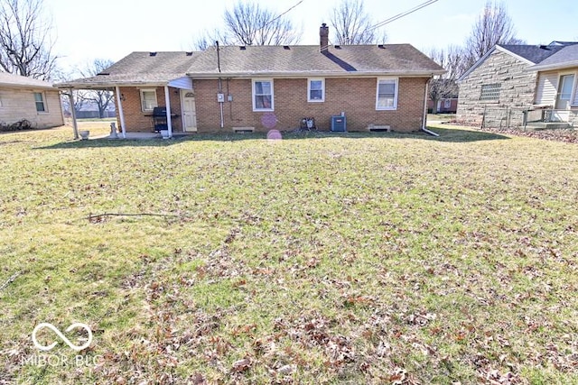 back of property featuring central air condition unit, a lawn, brick siding, and a chimney