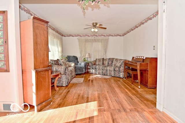 living room featuring light wood finished floors, visible vents, and ceiling fan