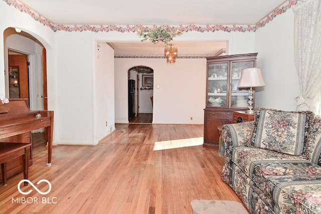 living area featuring arched walkways, light wood finished floors, and baseboards