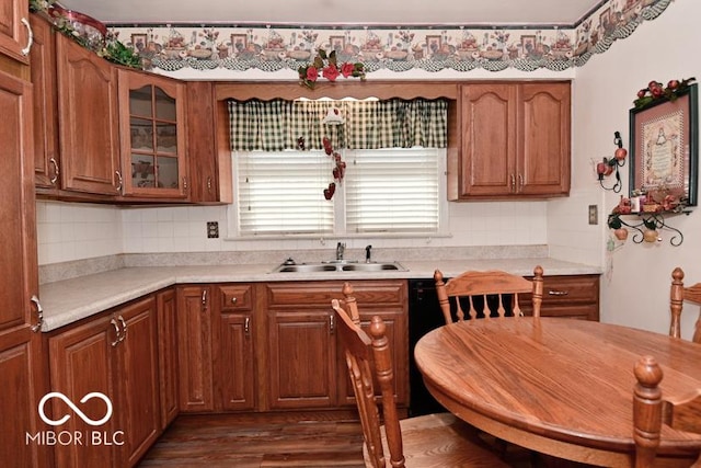 kitchen featuring decorative backsplash, light countertops, glass insert cabinets, and a sink