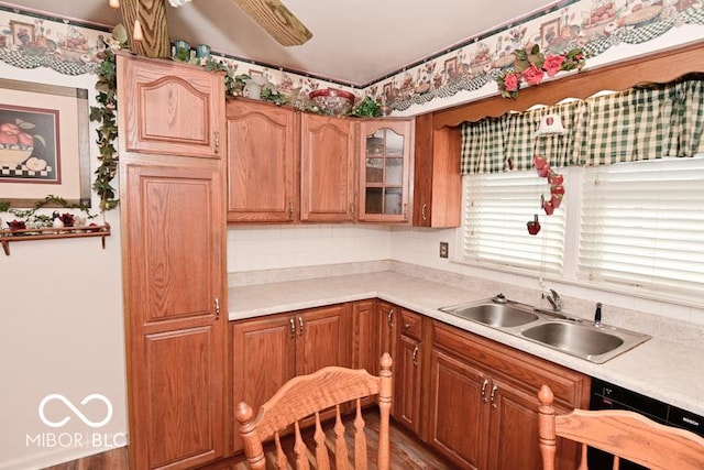 kitchen with a sink, decorative backsplash, light countertops, glass insert cabinets, and dishwasher