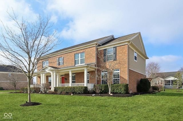 view of front of property featuring brick siding, covered porch, and a front yard