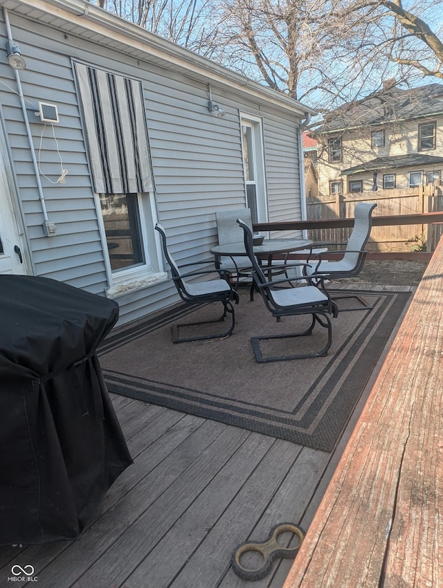 wooden terrace featuring fence and a grill