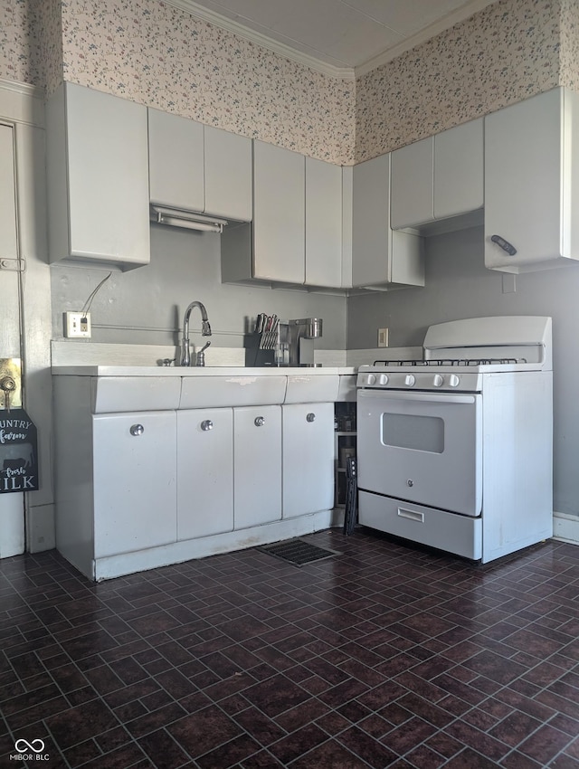 kitchen featuring brick patterned floor, ornamental molding, a sink, white gas range oven, and light countertops