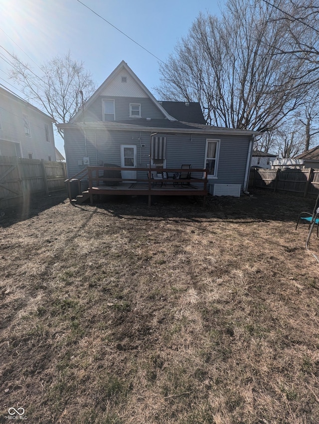 rear view of house featuring a yard, a wooden deck, and a fenced backyard