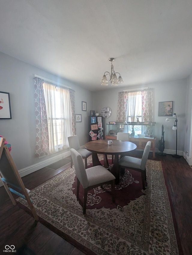 dining space featuring baseboards, an inviting chandelier, and wood finished floors