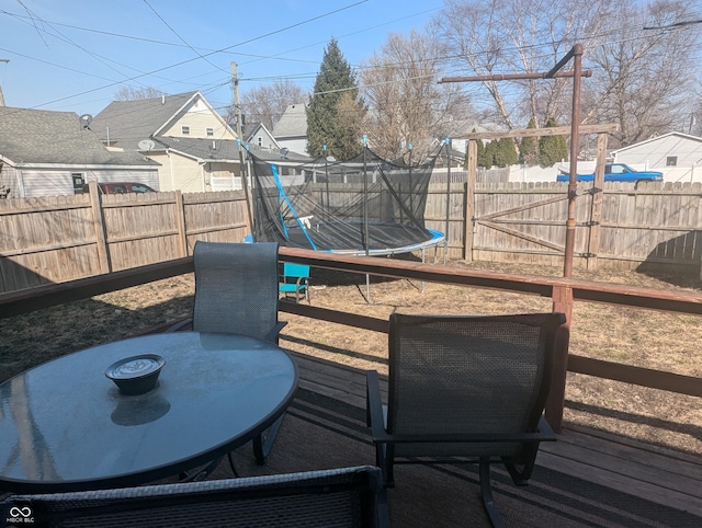 wooden deck with a trampoline and a fenced backyard