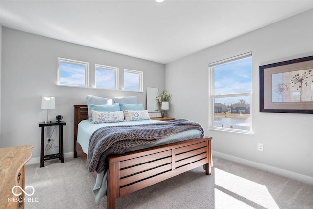 bedroom with multiple windows, baseboards, and light carpet