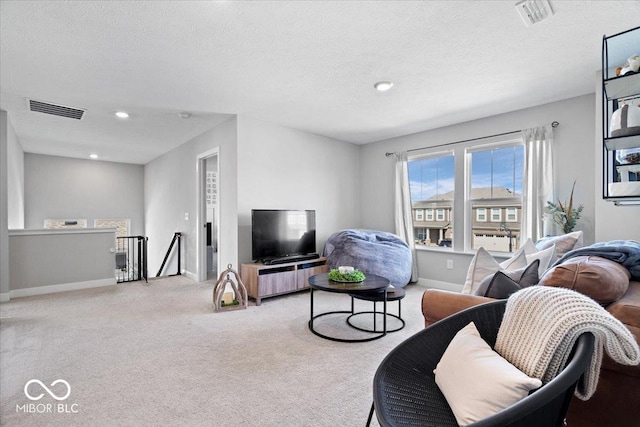 living area featuring visible vents, carpet floors, a textured ceiling, and baseboards